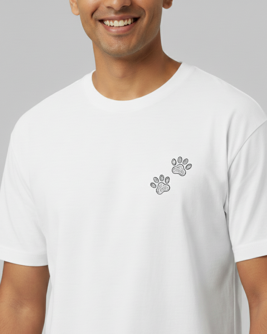 Person wearing a white t-shirt with a paw print design on a gray background