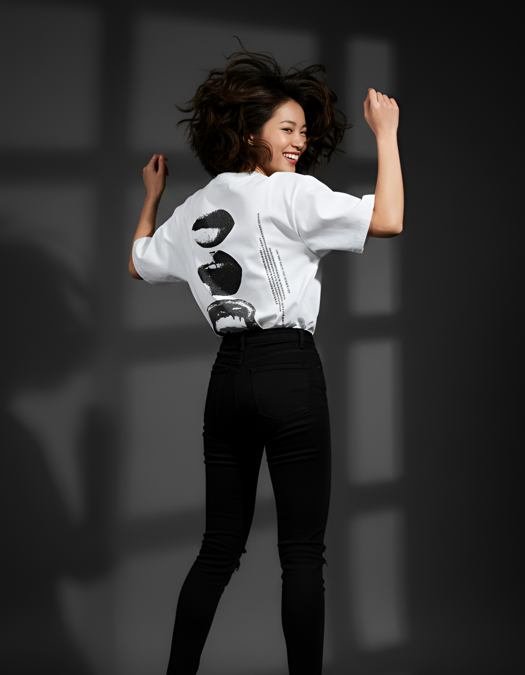 Person wearing a white shirt with black designs and black pants on a dark background
